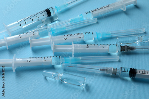 Disposable syringes with needles and ampules on light blue background, above view