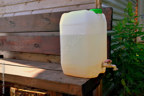Fotografie plastic canister with a tap on a bench in the garden