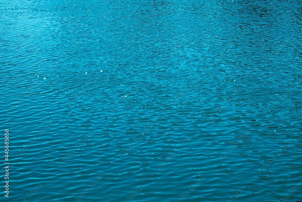 Blue water background. The calm surface of the sea. Ocean. Natural abstract background. Film grain and noise.