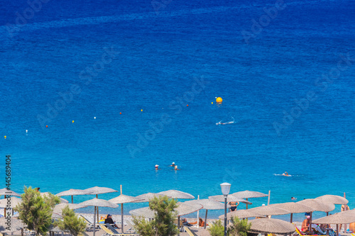 Kane umbrellas and sunbeds on an empty beach resort - vacation concept on Greece islands in Aegean and Mediterranean seas. Enidriou Beach in Rhodes city.