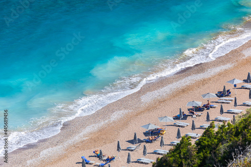 Colorful umbrellas and sunbeds on an empty beach resort - vacation concept on Greece islands in Aegean and Mediterranean seas. Akti Kanari Beach under Monte Smith in Rhodes city.