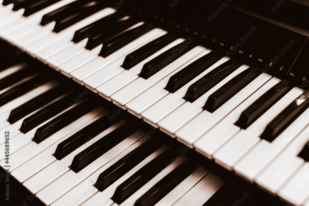 Close focus on upper row of piano with warm tone of black and white.