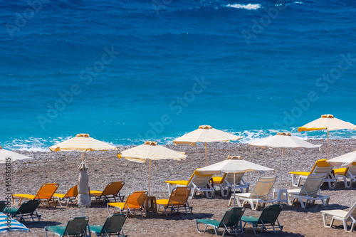 Colorful umbrellas and sunbeds on an empty beach resort - vacation concept on Greece islands in Aegean and Mediterranean seas