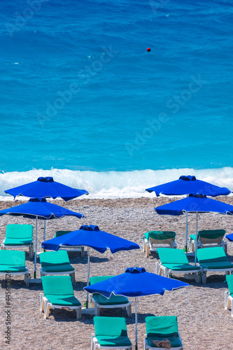 Colorful umbrellas and sunbeds on an empty beach resort - vacation concept on Greece islands in Aegean and Mediterranean seas