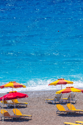 Colorful umbrellas and sunbeds on an empty beach resort - vacation concept on Greece islands in Aegean and Mediterranean seas