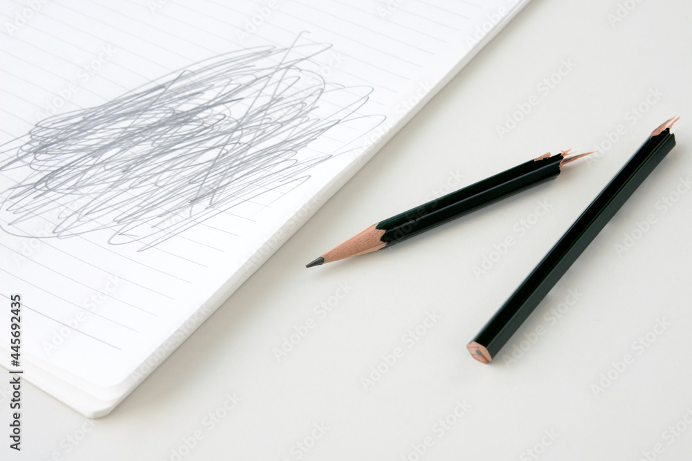 折られた鉛筆とぐちゃぐちゃ書きをされたノート 折られた鉛筆とぐちゃぐちゃ書きをされたノート