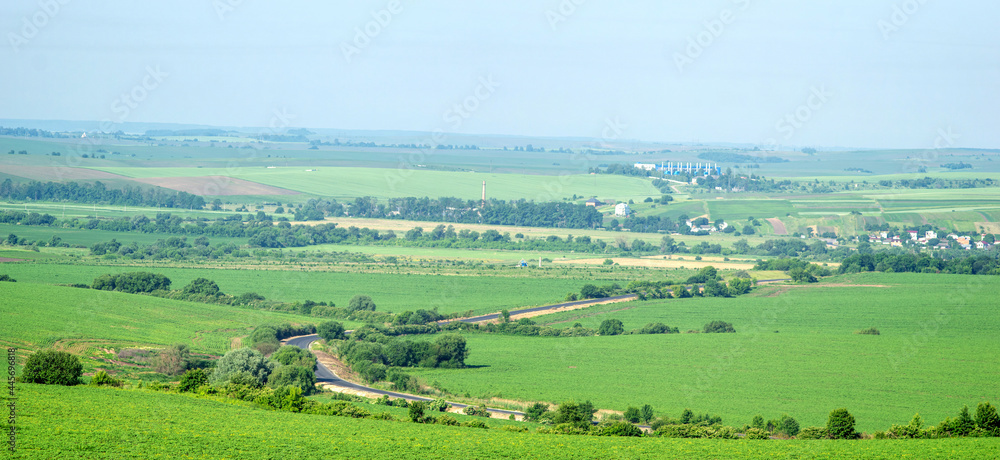 Asphalt road through a field against the background of a village in Ukraine