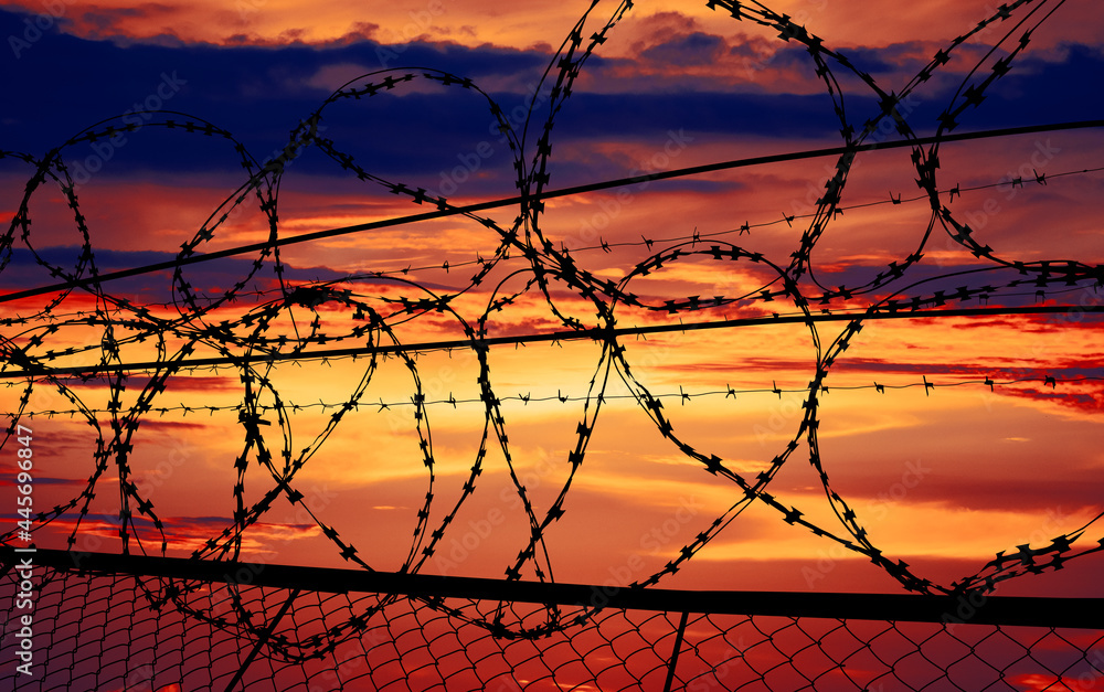 beautiful sunset behind the fence with barbed wire beautiful sunset behind the fence with barbed wire
