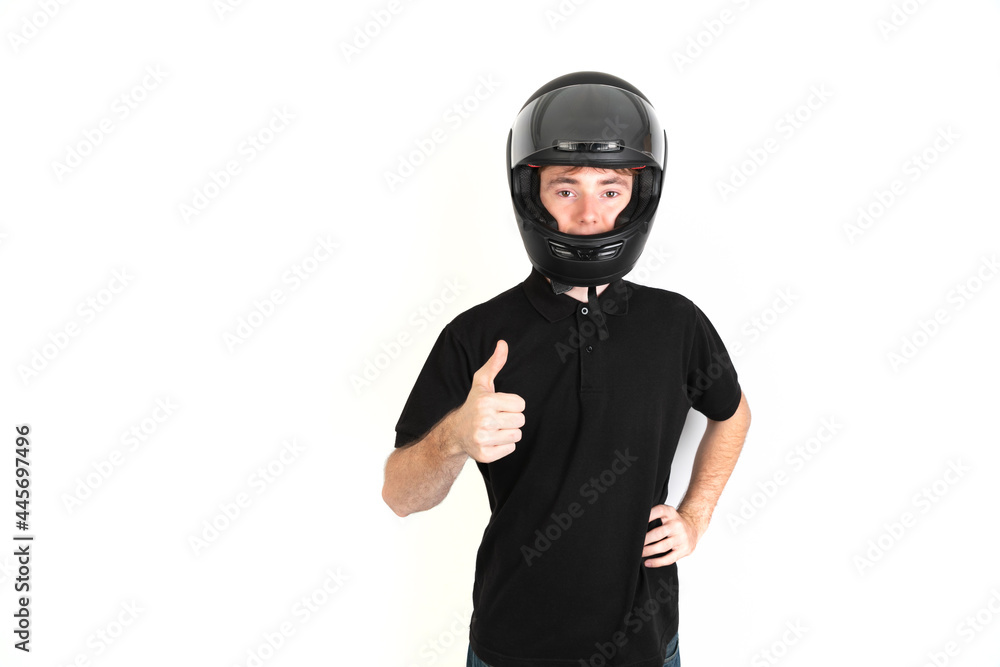 Teenager with a black motorcycle helmet with thumb up portrait, white background, 18-20 years old. White european guy. Teenager with a black motorcycle helmet with thumb up portrait, white background, 18-20 years old. White european guy.