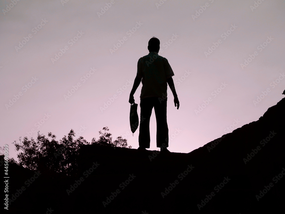 An old indian man holding bag on left hand at silhouette sky nature background, lifestyle concept image