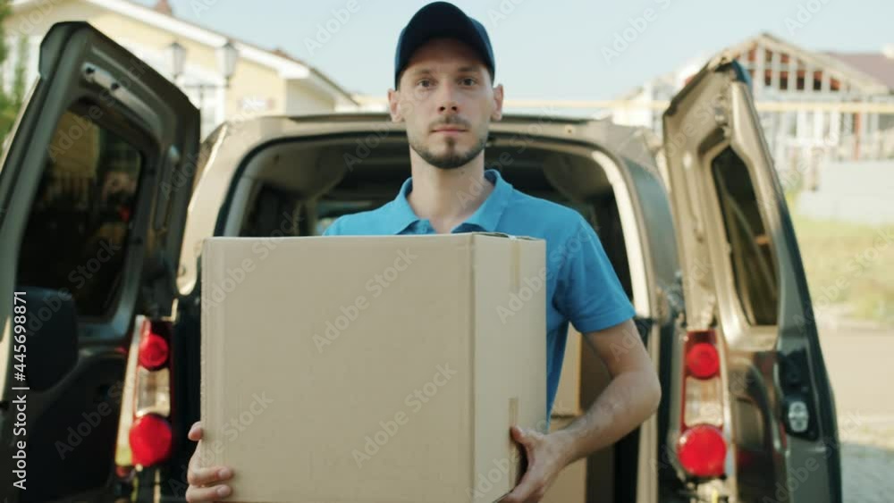 Dolly shot of deliveryman in uniform carrying parcel from van then knocking on front door waiting for customer. Shipment service and people concept. Dolly shot of deliveryman in uniform carrying parcel from van then knocking on front door waiting for customer. Shipment service and people concept.