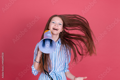 Little kid girl 13 years old in blue dress with brackets isolated on pink background shouting in megaphone happy positive cheerful