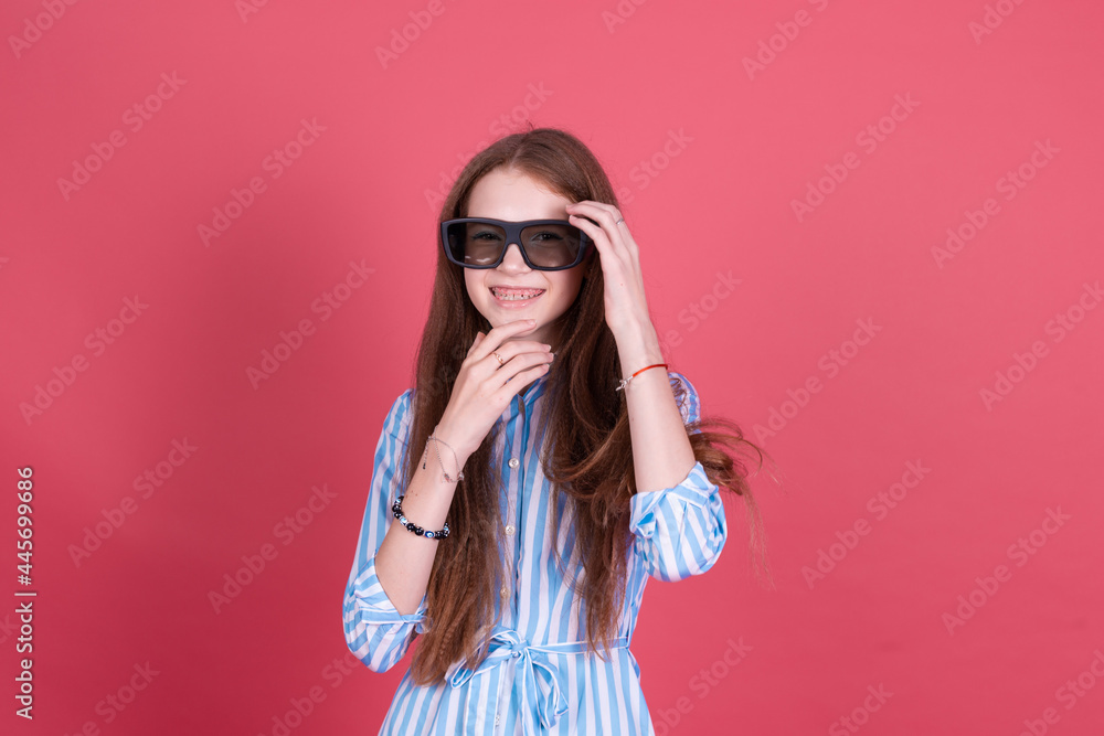 Little kid girl 13 years old in blue dress with brackets isolated on pink background wearing 3d cinema glasses happy smiling laugh Little kid girl 13 years old in blue dress with brackets isolated on pink background wearing 3d cinema glasses happy smiling laugh