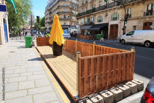 Terrasse éphémère estivale / extension de terrasse / contre-terrasse de café / bar / restaurant, en bois, vide, sur des places de stationnement le long d'un trottoir dans une rue de Paris (France)