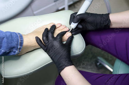 in the office of the master of pedicureFemale hardware pedicure in the salon. Cutting the cuticle of the thumbnail with a round cutter. Foot hygiene in the summer, foot care.
