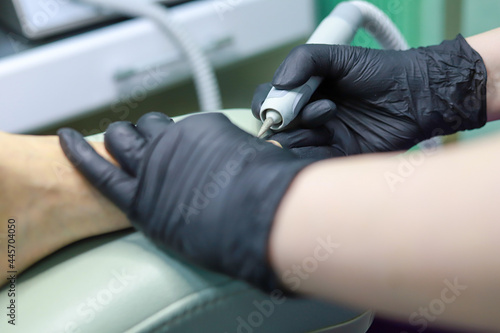 in the office of the master of pedicureFemale hardware pedicure in the salon. Cutting the cuticle of the thumbnail with a round cutter. Foot hygiene in the summer, foot care.