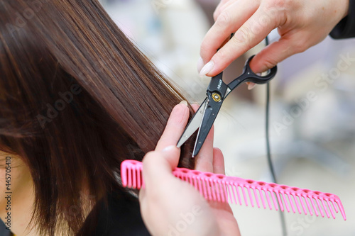 Stylist cutting split ends on her client at the salon. Close up.