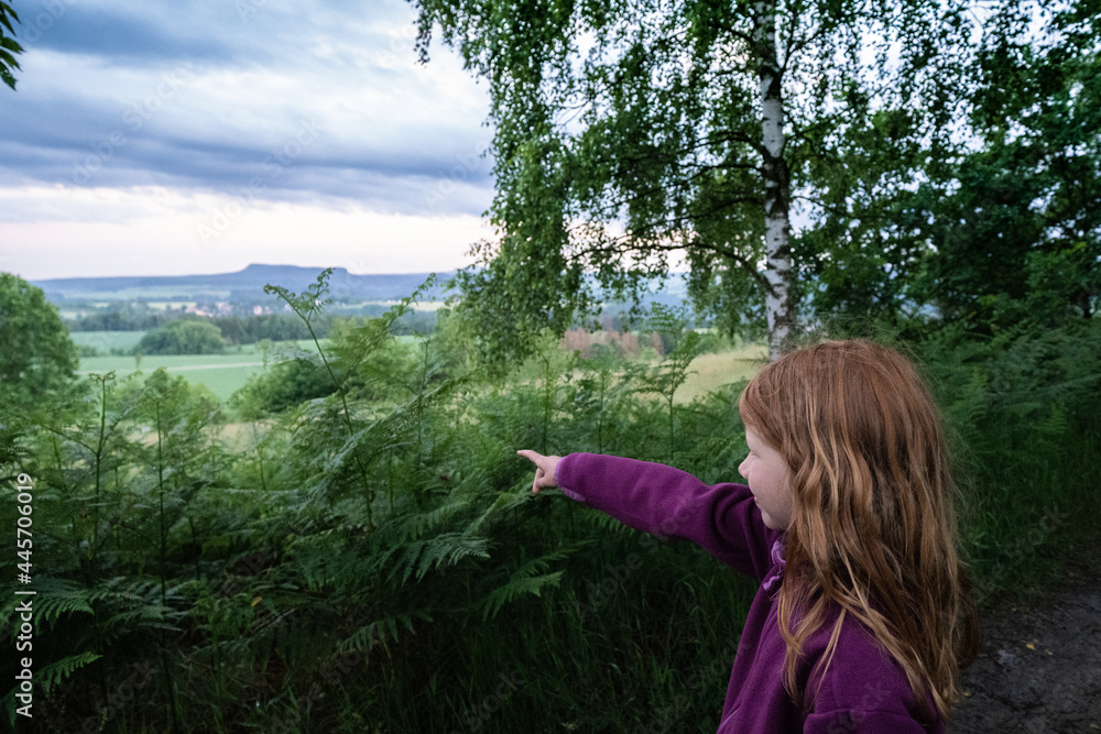 Porträt eines jungen, hübschen, manchmal nachdenklich oder frechen, rothaarigen Mädchens. Auf eigene Faust entdeckt sie spielerisch in einer lila Jacke die umliegende bergige Natur. Porträt eines jungen, hübschen, manchmal nachdenklich oder frechen, rothaarigen Mädchens. Auf eigene Faust entdeckt sie spielerisch in einer lila Jacke die umliegende bergige Natur.