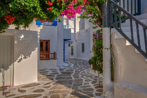 Beautiful traditional street in Greek island town. Whitewashed houses, bougainvillea in blossom, cobblestone. Mykonos, Greece