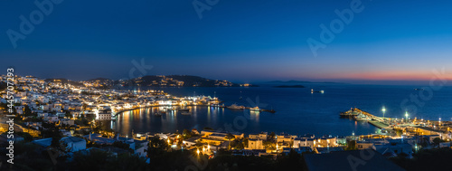 Beautiful night panorama of Mykonos, Greece, ships, port, whitewashed houses. Town lights up. Vacations, leisure, nightlife, Mediterranean lifestyle