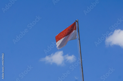 indonesian national flag flutter on flagepole at daylight with blue skya and cloud