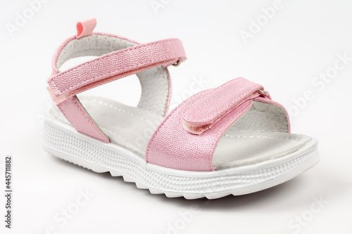Pink children's sandals made of shiny leather with Velcro fasteners, flat white soles, isolated on a white background. A pair of fashionable children's sandals for a comfortable walk. 