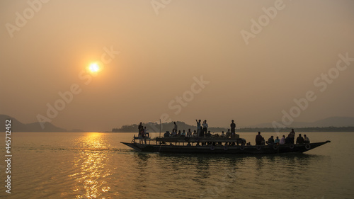 Scenic landscape view of wooden ferry crossing the mighty Brahmaputra river at sunset, Guwahati, Assam, India