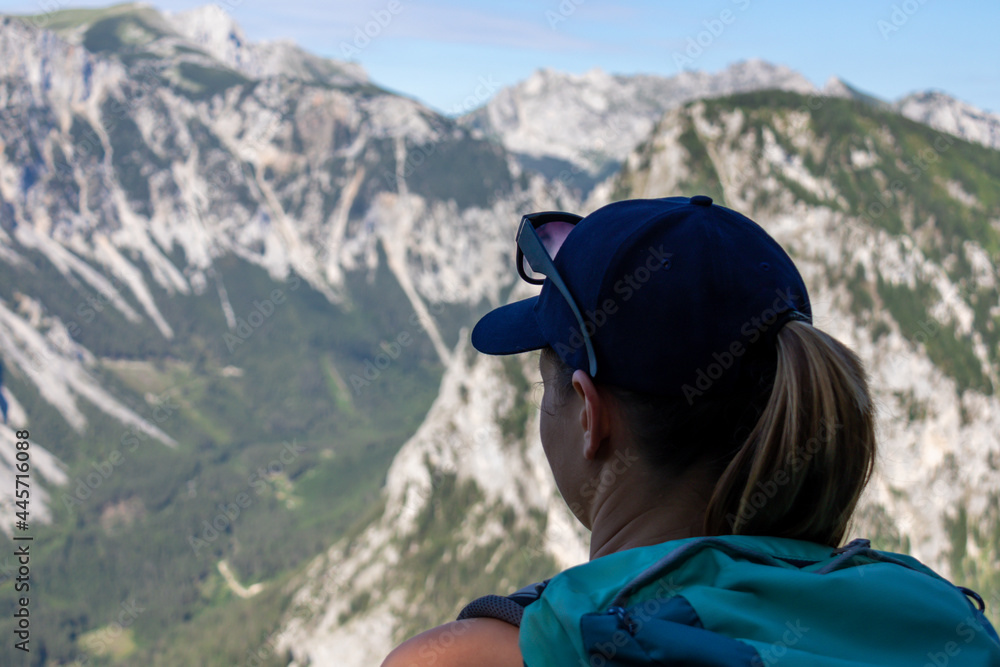 A woman with a hiking backpack admiring the view on the Alpine mountain chains in Austria, Hochschwab region. The slopes are partially overgrown with small bushes, higher parts baren. Happiness A woman with a hiking backpack admiring the view on the Alpine mountain chains in Austria, Hochschwab region. The slopes are partially overgrown with small bushes, higher parts baren. Happiness
