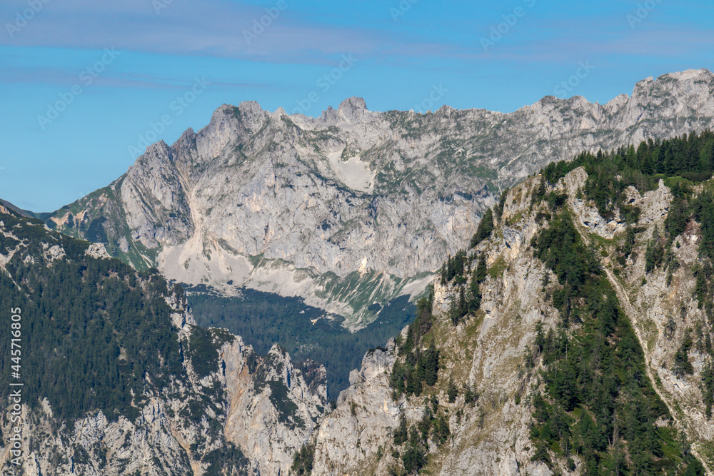 A panoramic view on the Alpine mountain chains in Austria, Hochschwab region. The slopes are partially overgrown with small bushes, higher parts baren. Clear and sunny day. Serenity. Hiking in Alps