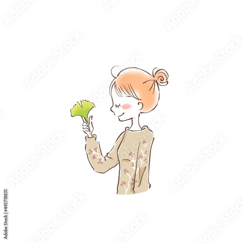 a young woman closing her yes and holding a autumn leave between her fingers