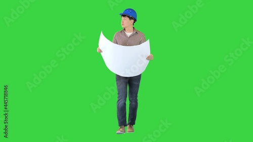 Engineer walking and looking at blueprint on a Green Screen, Chroma Key. photo