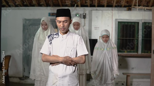 asian muslim family praying jamaah together at home. sholat or salah wearing white and hijab photo