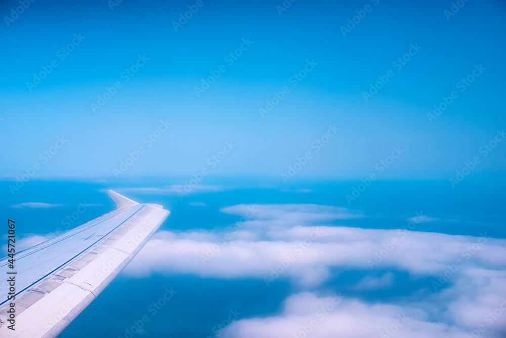 Airplane wing on the background of the sky with white clouds
