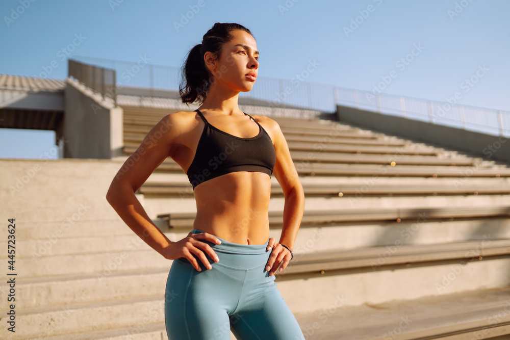 Fototapeta premium Young fitness woman exercising and stretching outdoors in the morning. Fit healthy athlete is doing workout on the street. Sport, Active life.