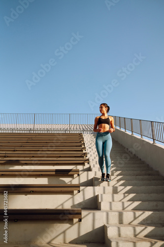 Young fitness woman exercising and stretching outdoors in the morning. Fit healthy athlete is doing workout on the street. Sport, Active life.