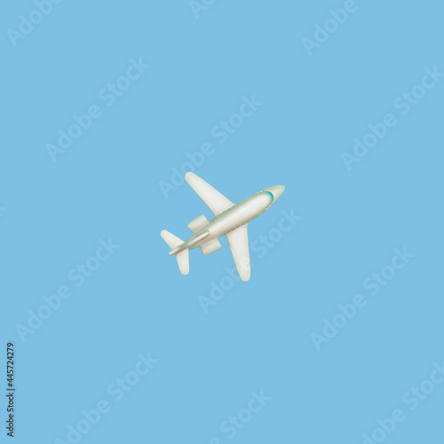 The plane on a blue background. Concept of air travel or travel. A look from above. A small toy liner. Flat lay