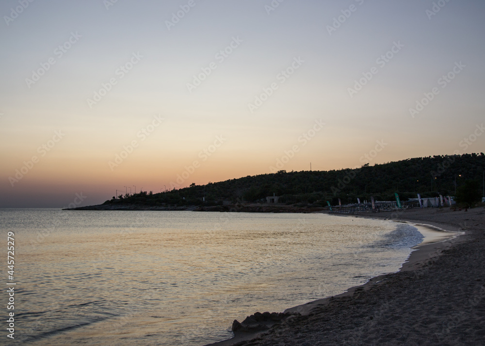 Sunbeds and umbrellas in a distant on the beach, sunset, peaceful nature, calm water, beautiful seascape, travel destination, summer vacation