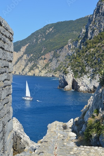 Portovenere, Italy. Mediterranean sea. Seascape with white sailboat and mountain on the background.