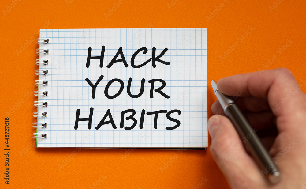Hack your habits symbol. Businessman writing words 'Hack your habits' on white note. Beautiful orange background. Business, psychology and hack your habits concept. Copy space. Hack your habits symbol. Businessman writing words 'Hack your habits' on white note. Beautiful orange background. Business, psychology and hack your habits concept. Copy space.