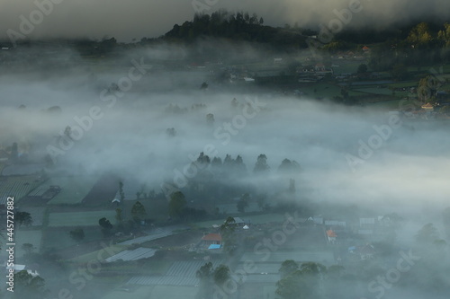 a foggy morning closes the village and trees in the valley of Mount Batur Bali