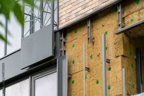 Installation of external wall thermal insulation with rock wool. Exterior passive house wall heat insulation with mineral wool. Insulation facade of multistory residential building. Energy efficiency photo