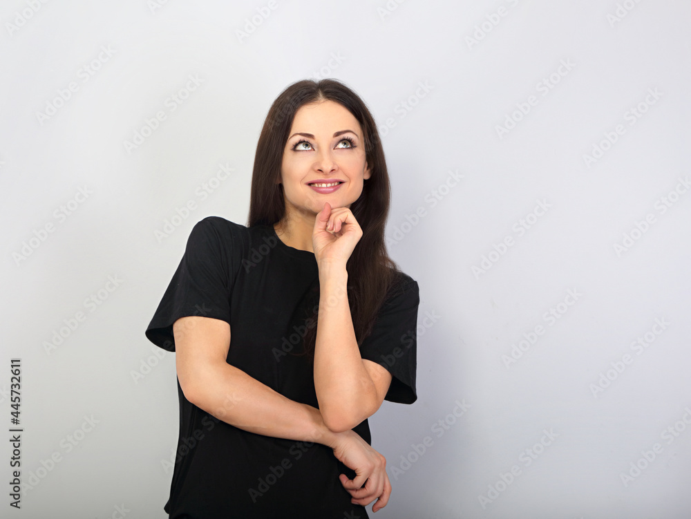 Beautiful happy casual woman in black t-shirt looking up with hand under the face on empty copy space background. Closeup Beautiful happy casual woman in black t-shirt looking up with hand under the face on empty copy space background. Closeup