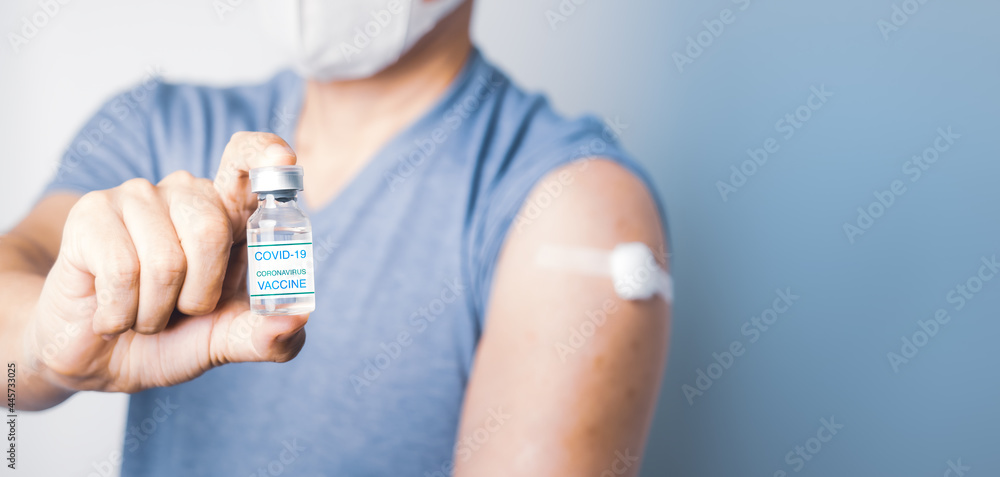 Asian man holding COVID-19 Vaccine bottle and show cotton on his arm after take injection Coronavirus vaccination immunity Asian man holding COVID-19 Vaccine bottle and show cotton on his arm after take injection Coronavirus vaccination immunity