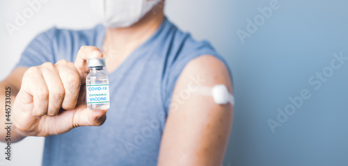 Asian man holding COVID-19 Vaccine bottle and show cotton on his arm after take injection Coronavirus vaccination immunity