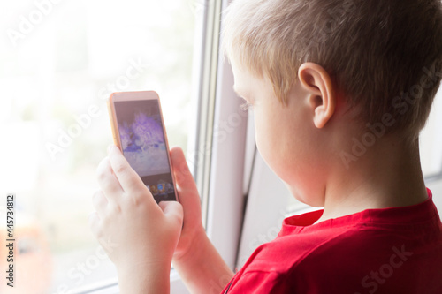 A boy with a phone in his hands, taking pictures on his mobile