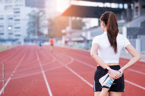 A young beautiful Asian woman in sports outfits doing stretching before workout outdoor in the park in the morning to get a healthy lifestyle. Healthy young woman warming up outdoors
