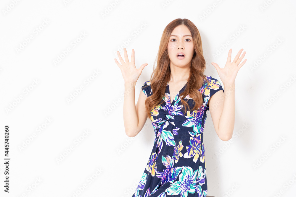 白い壁の前で驚いたジェスチャーをする、青いワンピースを着た若い女性 白い壁の前で驚いたジェスチャーをする、青いワンピースを着た若い女性