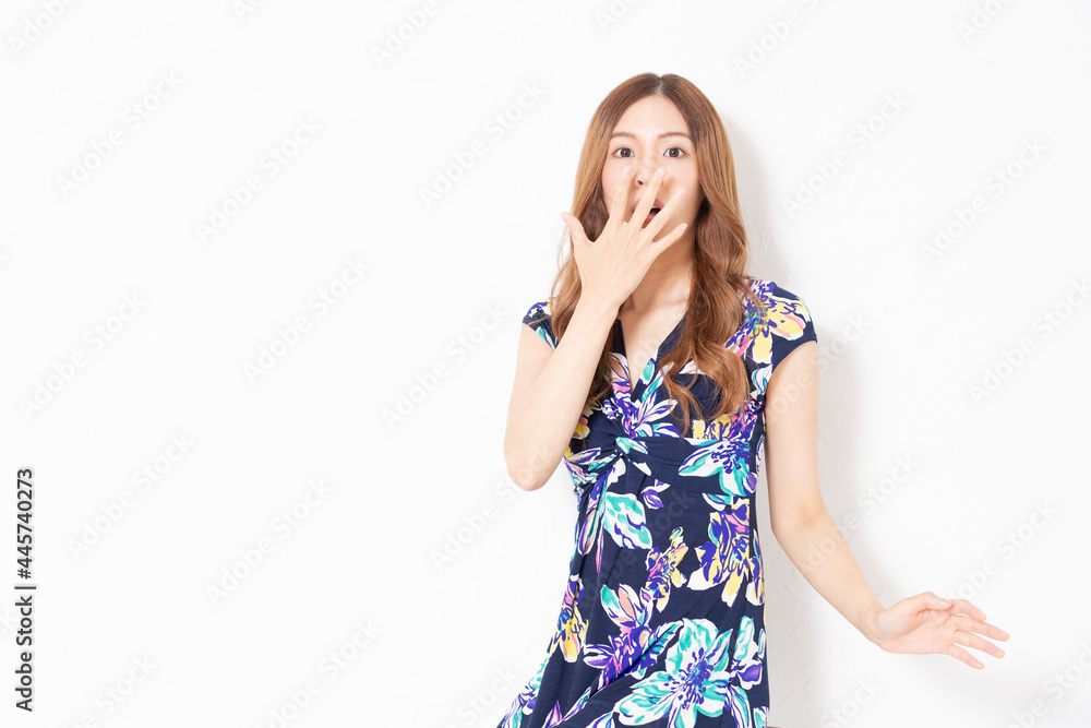 白い壁の前で驚いたジェスチャーをする、青いワンピースを着た若い女性 白い壁の前で驚いたジェスチャーをする、青いワンピースを着た若い女性