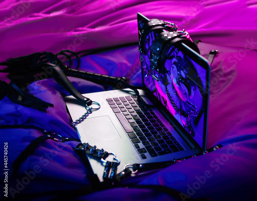 A set of BDSM toys for sex on a laptop on a bright neon background photo