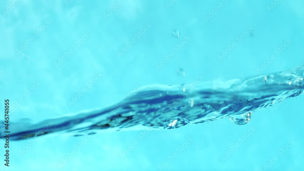 Slow motion video of water waves with splashes and falling drops on a blue background. Slow motion video of water waves with splashes and falling drops on a blue background.